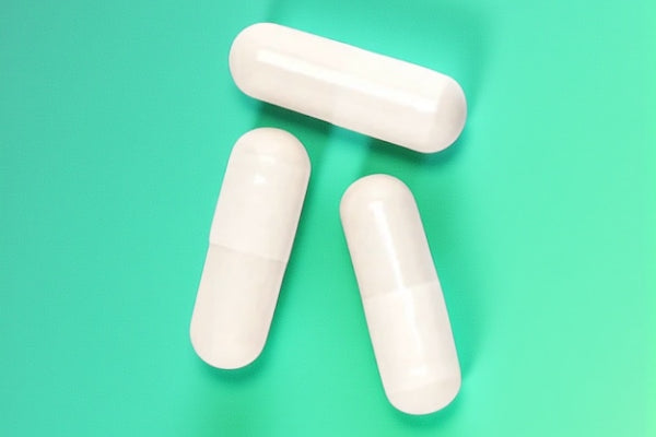 3 White Plenity Pills On Colored Green and Blue background